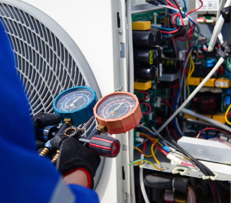 Air conditioner service .The air conditioner technician is using a gauge to measure the refrigerant pressure. air compressor.